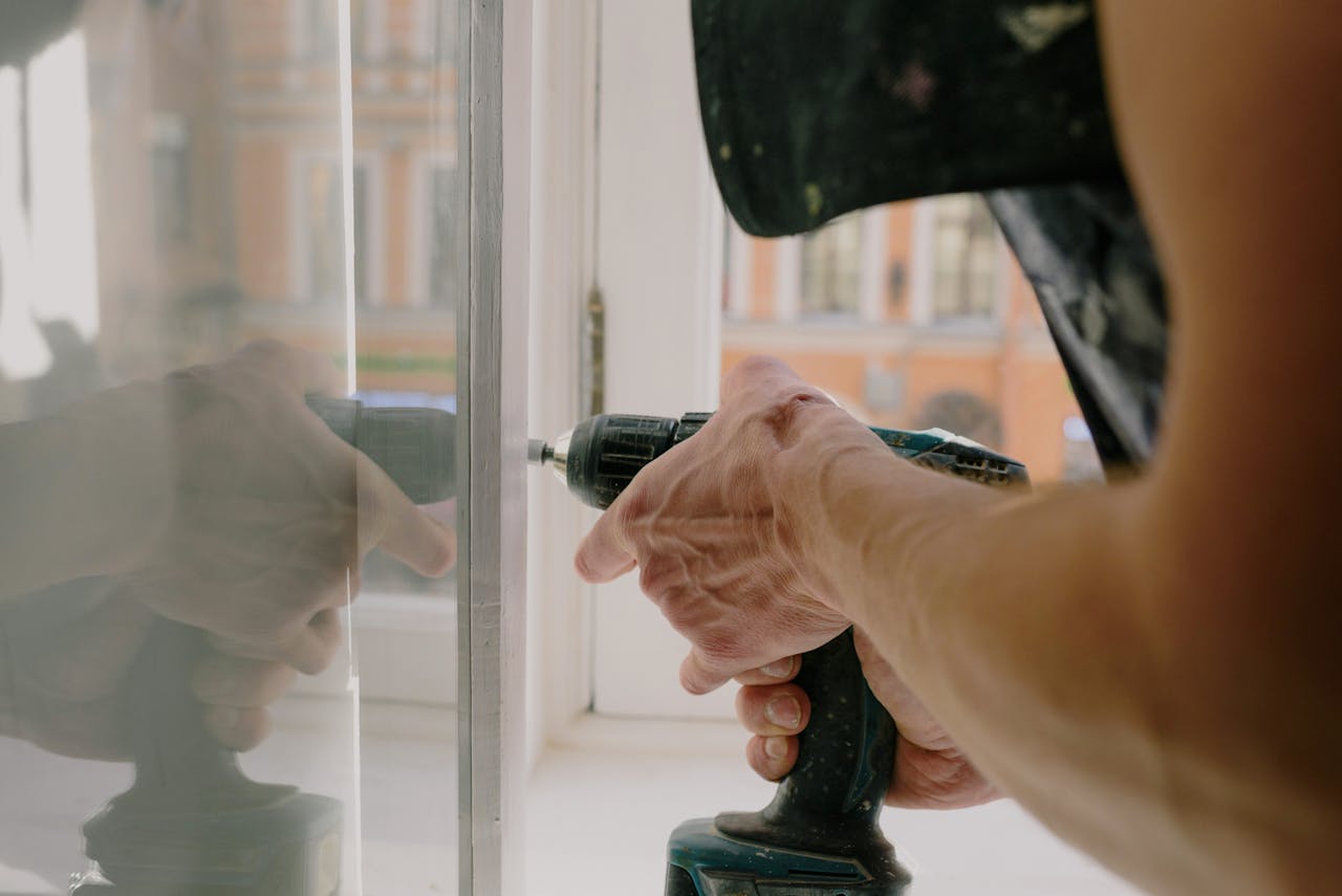 why-choose-us-01 Unrecognizable professional male worker assembling white window with cordless screwdriver with drill near windowsill with reflection on glass during repair works in apartment